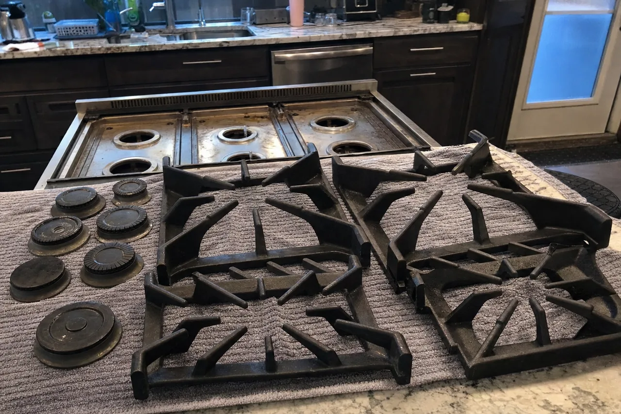 The same strip-down mirrored - grates on a towel and the bare burner wells of a rangetop in a dark-cabinet kitchen